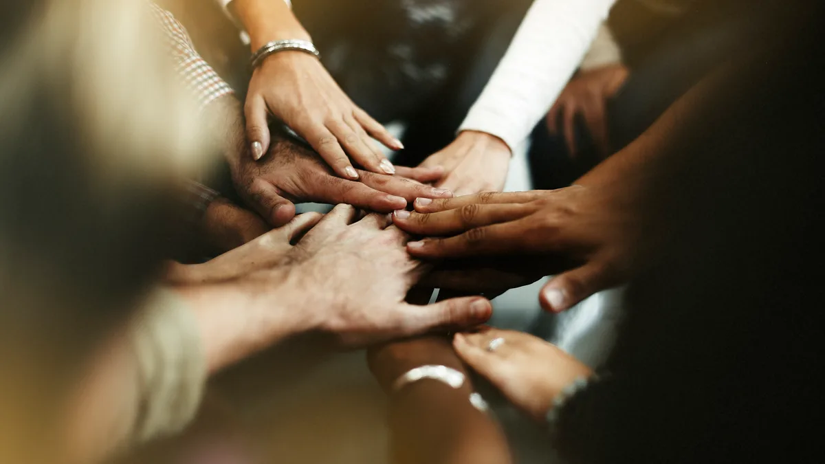 Hands layered together to represent collective care, solidarity, and shared action - ACHFN, African & Caribbean Heritage Food Network